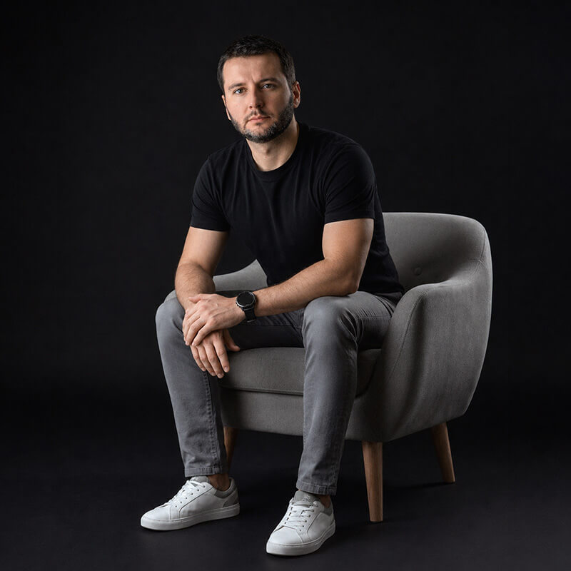 Marcelo Benez, cofundador da Machine Maker, sentado em poltrona, roupa preta e fundo escuro
